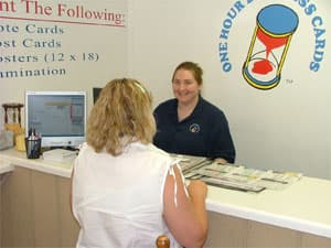 A One Hour Business Cards designer smiling while helping a customer at the front counter