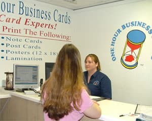 A designer at the counter talking through a card design with a customer